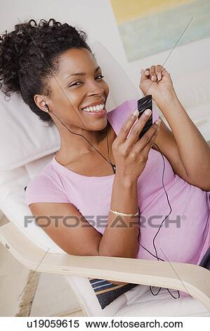 Stock Photography - Young smiling woman listening music. Fotosearch