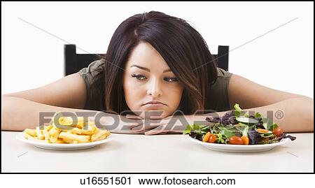 Young woman choosing between healthy and unhealthy food View Large Photo Image Stock Image - Young woman choosing between healthy and unhealthy food. Fotosearch