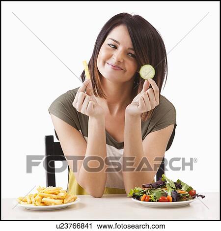 Young woman choosing between healthy and unhealthy food View Large Photo Image Stock Image - Young woman choosing between healthy and unhealthy food. Fotosearch