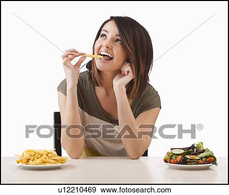 Young woman choosing between healthy and unhealthy food View Large Photo Image Stock Photo - Young woman choosing between healthy and unhealthy food. Fotosearch