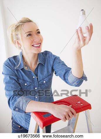Young woman holding light bulb, studio shot View Large Photo Image Stock Photograph - Young woman holding light bulb, studio shot. Fotosearch