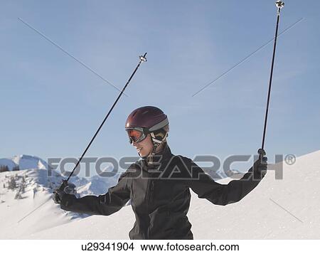 Picture - Young woman in ski gear at top of mountain. Fotosearch