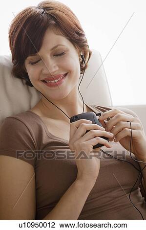 Young woman listening music on armchair View Large Photo Image Stock Image - Young woman listening music on armchair. Fotosearch