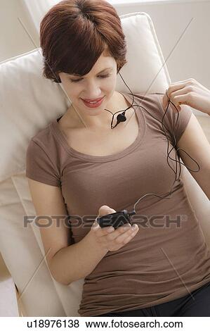 Young woman listening music on armchair View Large Photo Image Stock Photo - Young woman listening music on armchair. Fotosearch