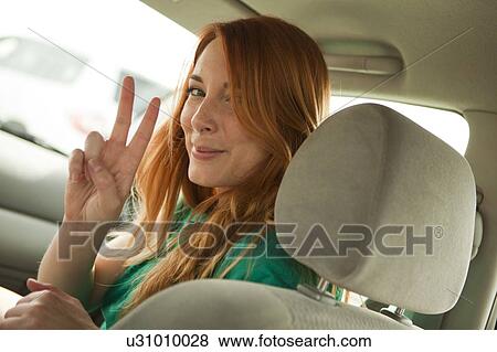 Young woman looking over shoulder and making peace sign View Large Photo Image Stock Photo - Young woman looking over shoulder and making peace sign. Fotosearch