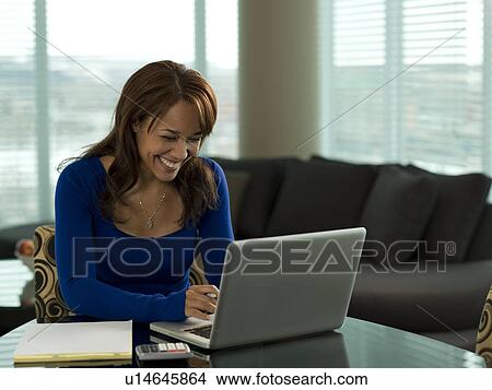 Picture - Young woman paying bills at kitchen table. Fotosearch