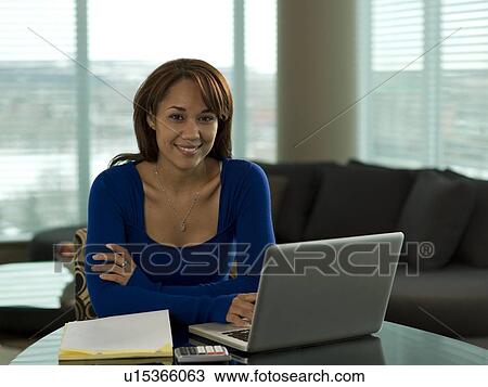 Young woman paying bills at kitchen table View Large Photo Image Stock Image - Young woman paying bills at kitchen table. Fotosearch