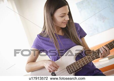 Stock Image - Young woman playing electric guitar. Fotosearch