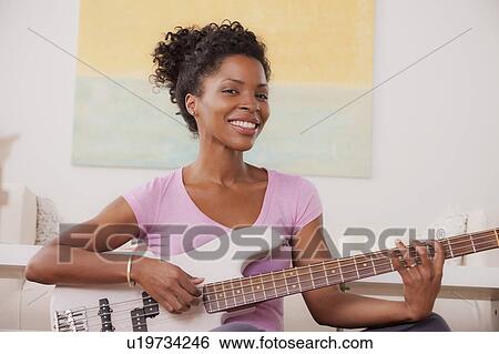 Stock Photograph - Young woman playing electric guitar. Fotosearch