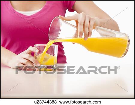 Stock Photo - Young woman pouring juice into glass. Fotosearch