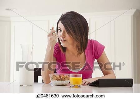 Stock Image - Young woman preparing breakfast. Fotosearch
