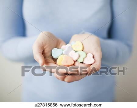 Stock Photograph - Young woman showing handful of cookie hearts. Fotosearch