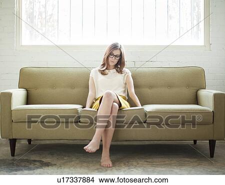 Picture - Young woman sitting on sofa. Fotosearch