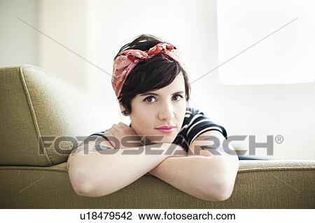 Young woman sitting on sofa View Large Photo Image Stock Image - Young woman sitting on sofa. Fotosearch