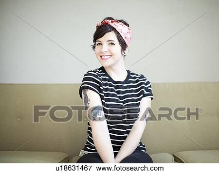 Stock Photo - Young woman sitting on sofa. Fotosearch