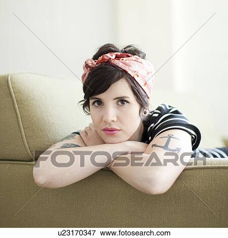 Young woman sitting on sofa View Large Photo Image Stock Photo - Young woman sitting on sofa. Fotosearch
