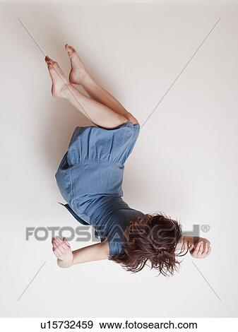 Stock Photo - Young woman wearing blue dress falling upside down. Fotosearch