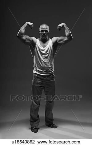 Stock Image - Athlete displaying arm muscles indoors. Fotosearch
