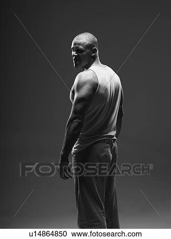Stock Image - Athlete frowning over shoulder indoors. Fotosearch