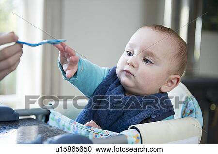 Baby reaching for spoon at table View Large Photo Image Stock Image - Baby reaching for spoon at table. Fotosearch