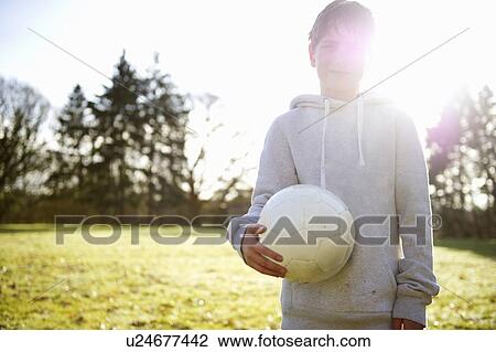 Boy carrying soccer ball in meadow View Large Photo Image Stock Image - Boy carrying soccer ball in meadow. Fotosearch