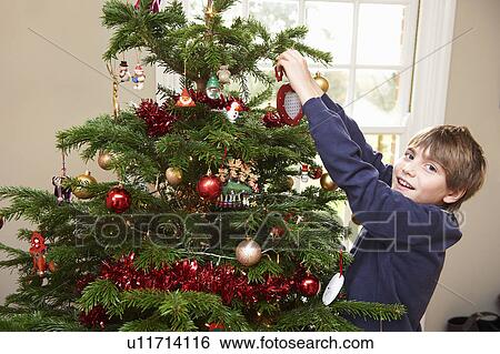 Stock Photograph - Boy decorating Christmas tree. Fotosearch