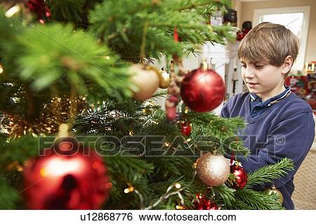Stock Photograph - Boy decorating Christmas tree. Fotosearch