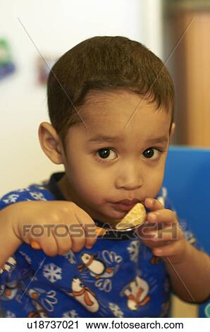 Boy eating fruit in kitchen View Large Photo Image Stock Image - Boy eating fruit in kitchen. Fotosearch