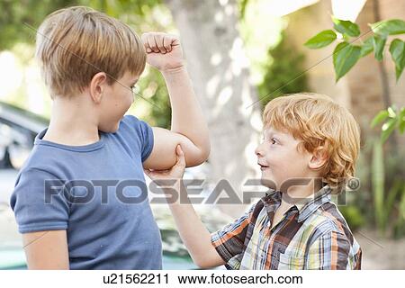 Stock Image - Boy feeling brothers biceps outdoors. Fotosearch