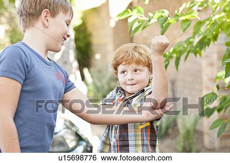 Boy feeling brothers biceps outdoors View Large Photo Image Stock Photograph - Boy feeling brothers biceps outdoors. Fotosearch