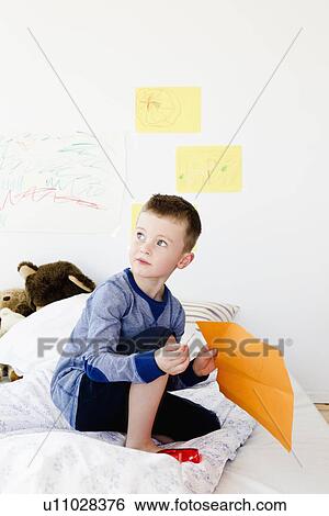 Stock Photograph - Boy holding drawing on bed. Fotosearch