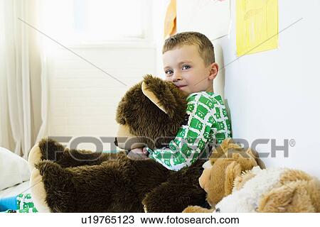Stock Image - Boy hugging teddy bear in bed. Fotosearch