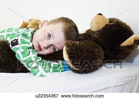 Boy hugging teddy bear in bed View Large Photo Image Stock Photo - Boy hugging teddy bear in bed. Fotosearch