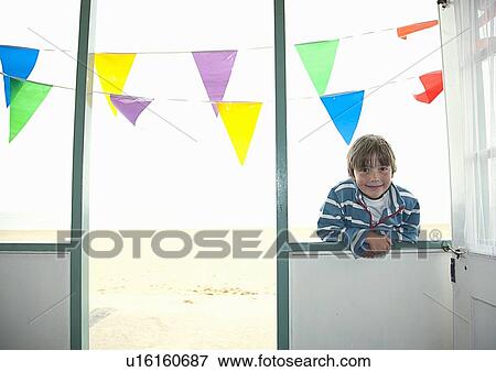 Stock Photo - Boy leaning in windowsill of hut. Fotosearch