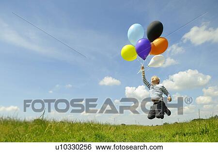 Stock Photograph - Boy playing with balloons in meadow. Fotosearch