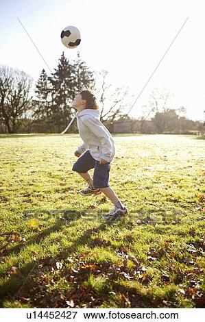 Boy playing with soccer ball in meadow View Large Photo Image Stock Photo - Boy playing with soccer ball in meadow. Fotosearch