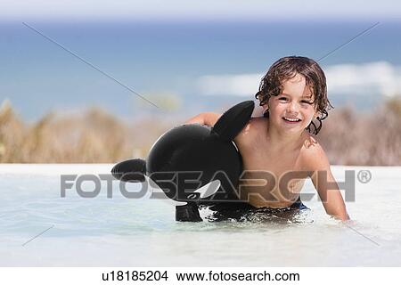 Boy playing with toy whale in pool View Large Photo Image Picture - Boy playing with toy whale in pool. Fotosearch