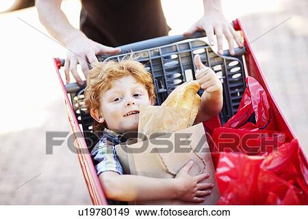 Stock Photo - Boy riding in shopping cart. Fotosearch