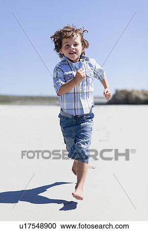Stock Image - Boy running on sandy beach. Fotosearch