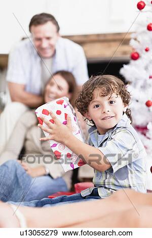 Boy shaking wrapped Christmas gift View Large Photo Image Stock Photo - Boy shaking wrapped Christmas gift. Fotosearch