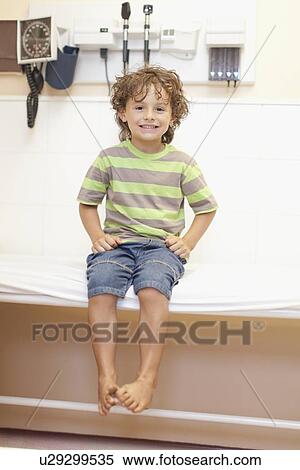 Boy sitting on table in doctors office View Large Photo Image Stock Photography - Boy sitting on table in doctors office. Fotosearch