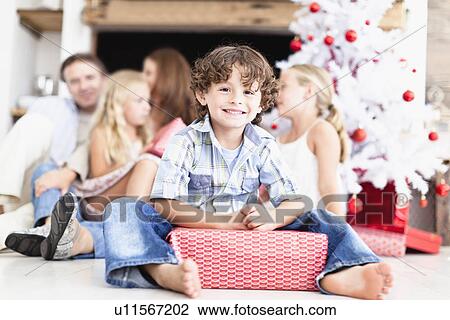 Boy sitting with wrapped Christmas gift View Large Photo Image Stock Image - Boy sitting with wrapped Christmas gift. Fotosearch