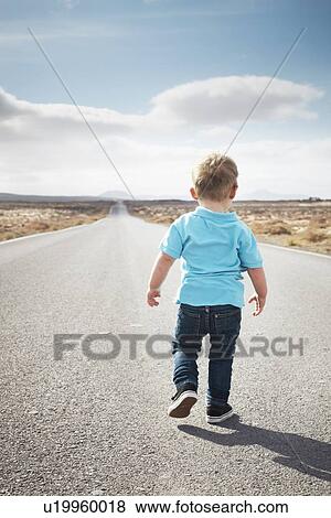 Stock Photo - Boy walking on paved rural road. Fotosearch