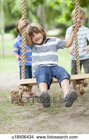 Boys pushing friend on tree swing View Large Photo Image Picture - Boys pushing friend on tree swing. Fotosearch