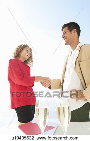 Stock Image - Business people shaking hands outdoors. Fotosearch