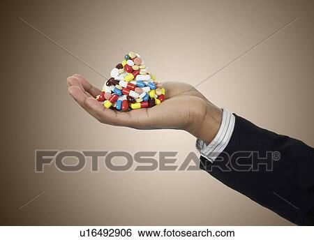 Stock Photograph - Businessman holding stack of pills. Fotosearch