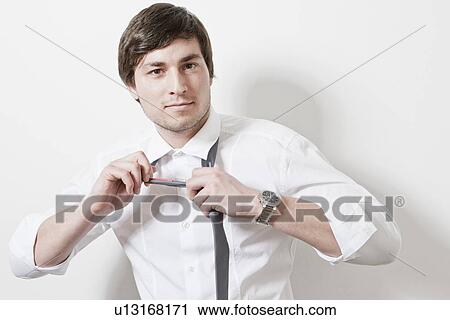 Businessman loosening tie in office View Large Photo Image Stock Image - Businessman loosening tie in office. Fotosearch