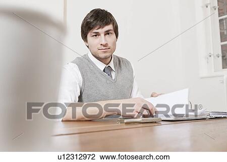 Businessman reading papers at desk View Large Photo Image Stock Image - Businessman reading papers at desk. Fotosearch