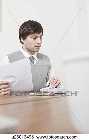 Stock Photography - Businessman reading papers at desk. Fotosearch