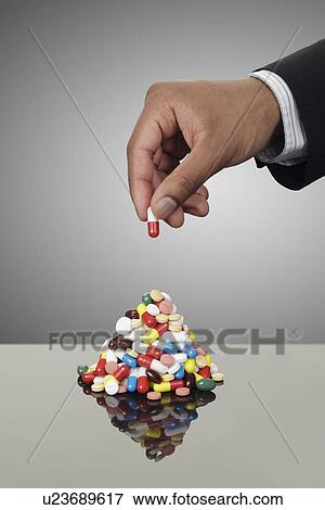 Businessman stacking pills on counter View Large Photo Image Stock Photo - Businessman stacking pills on counter. Fotosearch